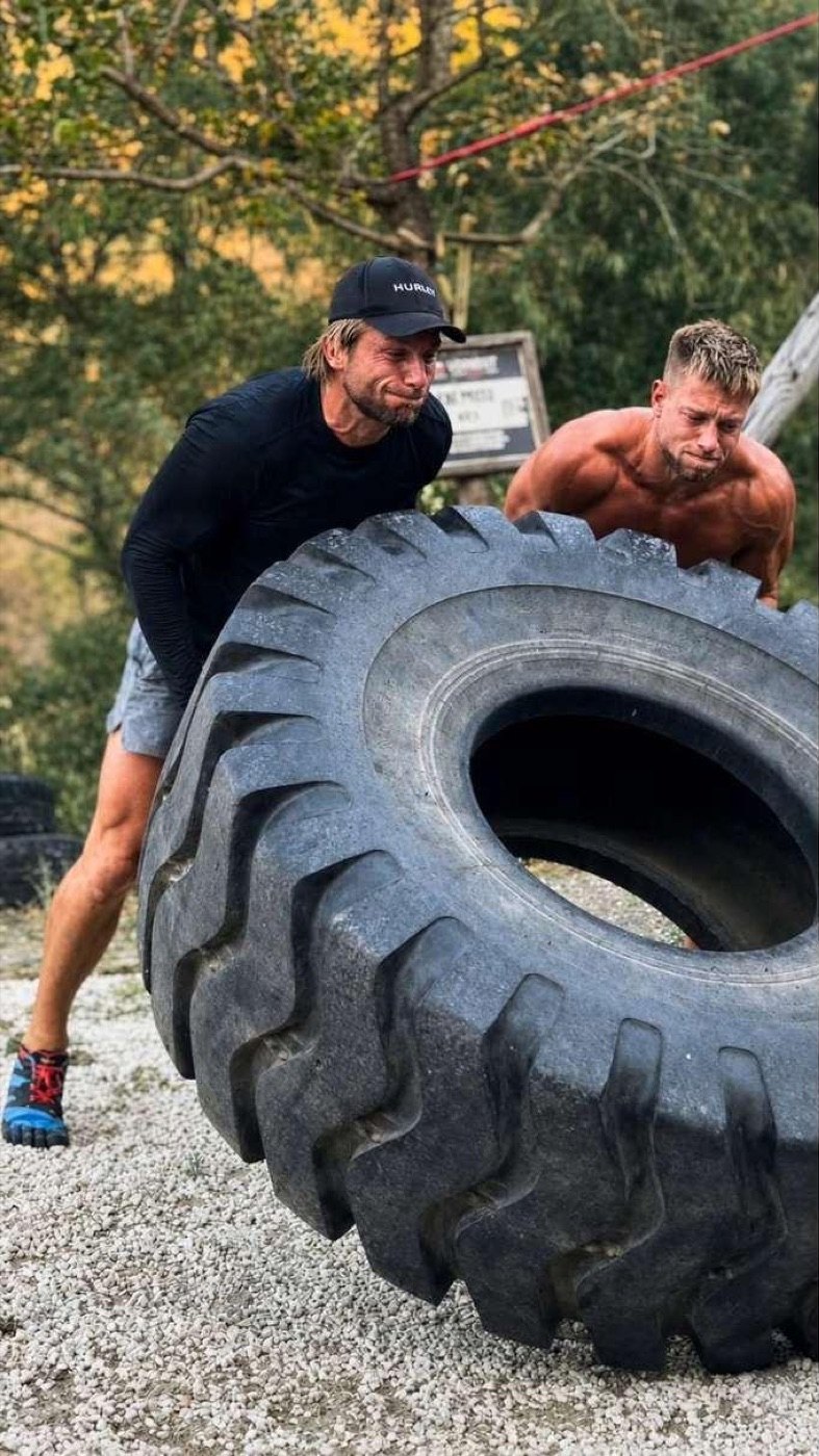 Men flipping a heavy tyre on the course