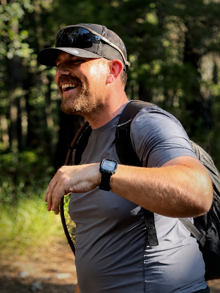 Vinny on a woodland trail, pack on, mid laugh